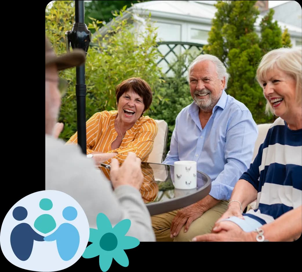 Four elderly people sitting at an outdoor table, laughing and enjoying a conversation