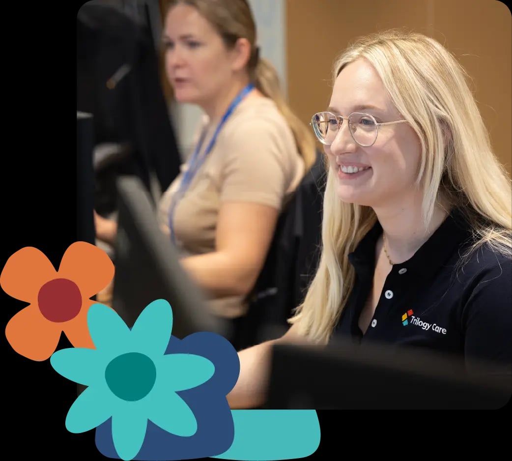 Trilogy Care support worker smiling in the office, with flower icons on the side