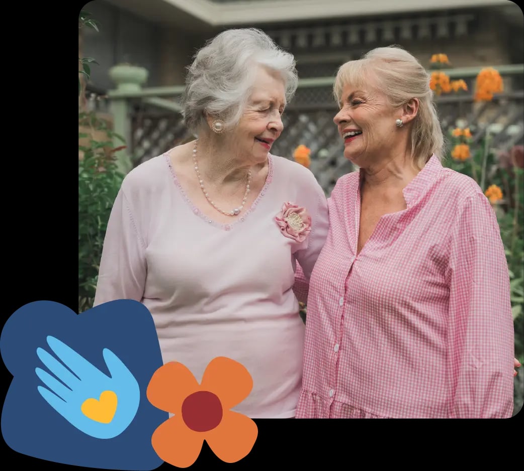 Paula Duncan and an elderly woman smiling in a garden, looking at each other, representing friendship and home care support