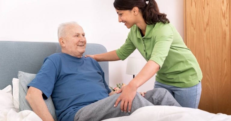 elderly man being helped into bed by carer