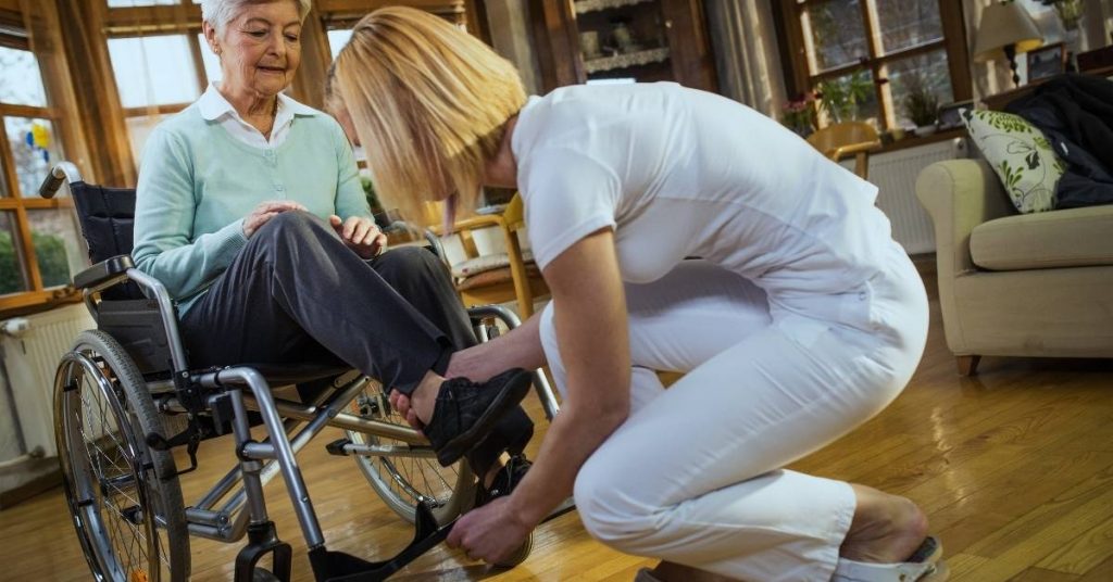 carer helping older woman into wheelchair
