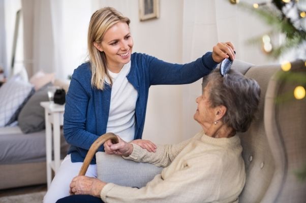 carer assisting elderly woman in home